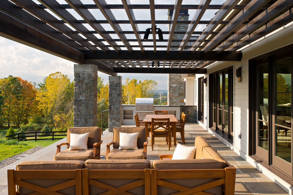 Cette image montre une terrasse rustique avec du carrelage et une pergola.