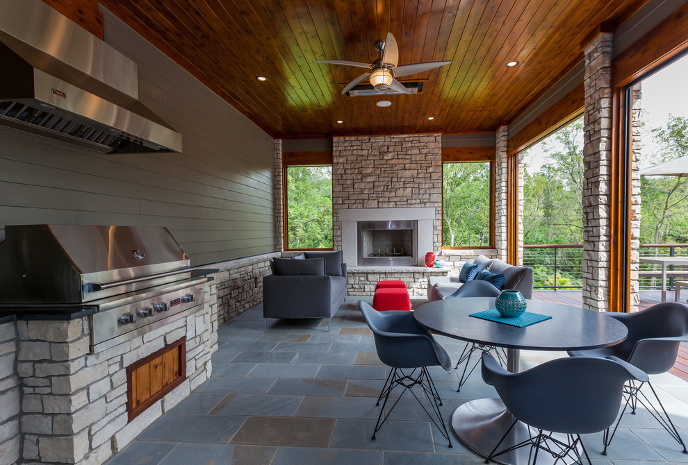 Aménagement d'une terrasse arrière contemporaine de taille moyenne avec une cuisine d'été, des pavés en pierre naturelle et une extension de toiture.