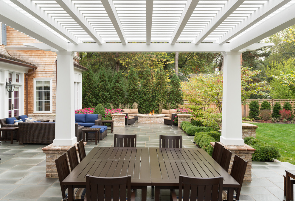 На фото: большой двор на заднем дворе в классическом стиле с местом для костра, покрытием из плитки и навесом