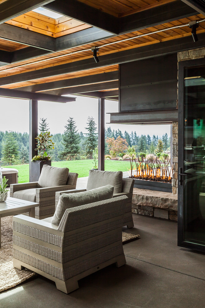 Expansive contemporary back patio in Portland with a fire feature, concrete slabs and a roof extension.