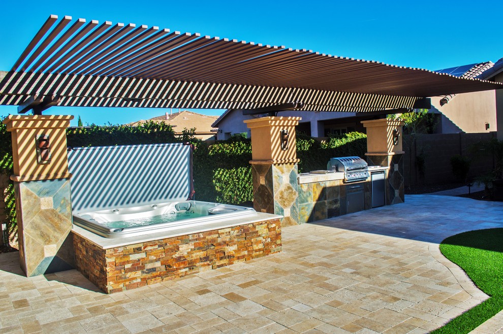 Exemple d'une terrasse arrière chic de taille moyenne avec une cuisine d'été, des pavés en brique et une pergola.