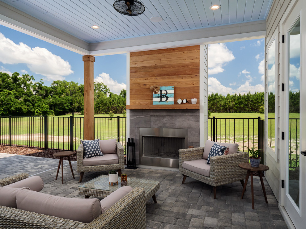 Idée de décoration pour une grande terrasse arrière champêtre avec une cheminée, des pavés en béton et une extension de toiture.