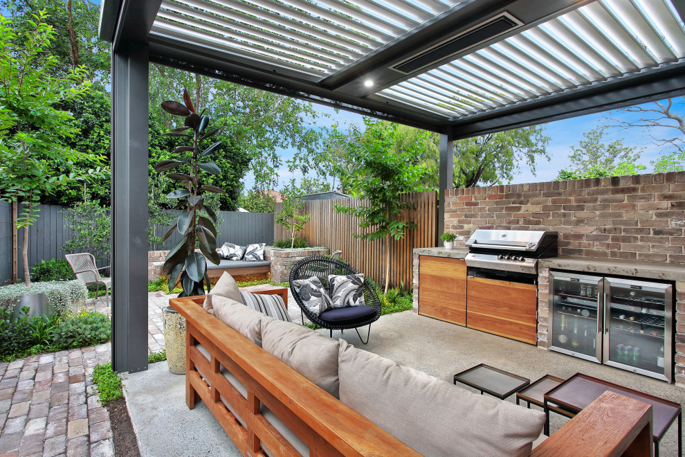Ispirazione per un patio o portico contemporaneo di medie dimensioni e dietro casa con pavimentazioni in mattoni e un tetto a sbalzo
