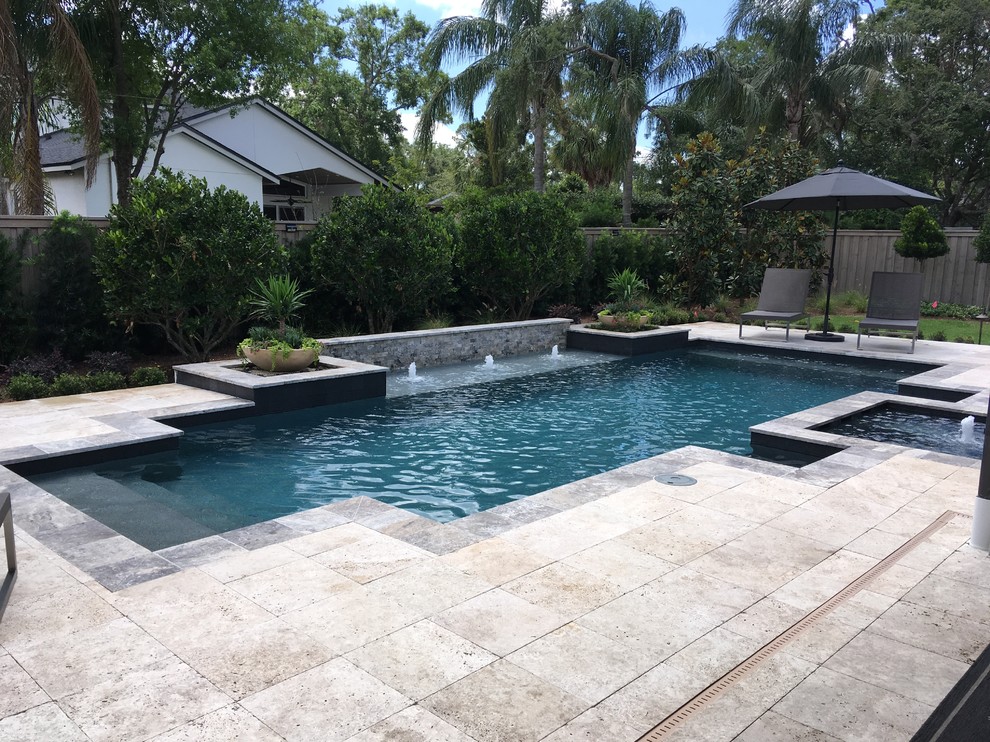 Großer Moderner Pool hinter dem Haus mit Wasserspiel und Natursteinplatten in Orlando