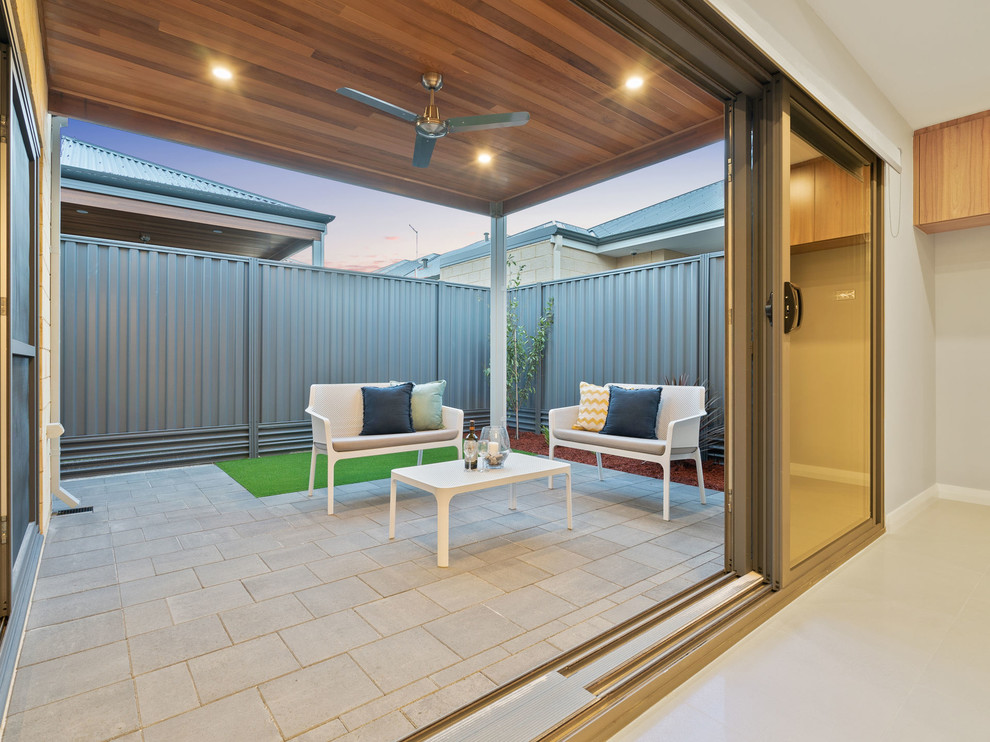 Immagine di un piccolo patio o portico moderno dietro casa con pavimentazioni in mattoni e un tetto a sbalzo