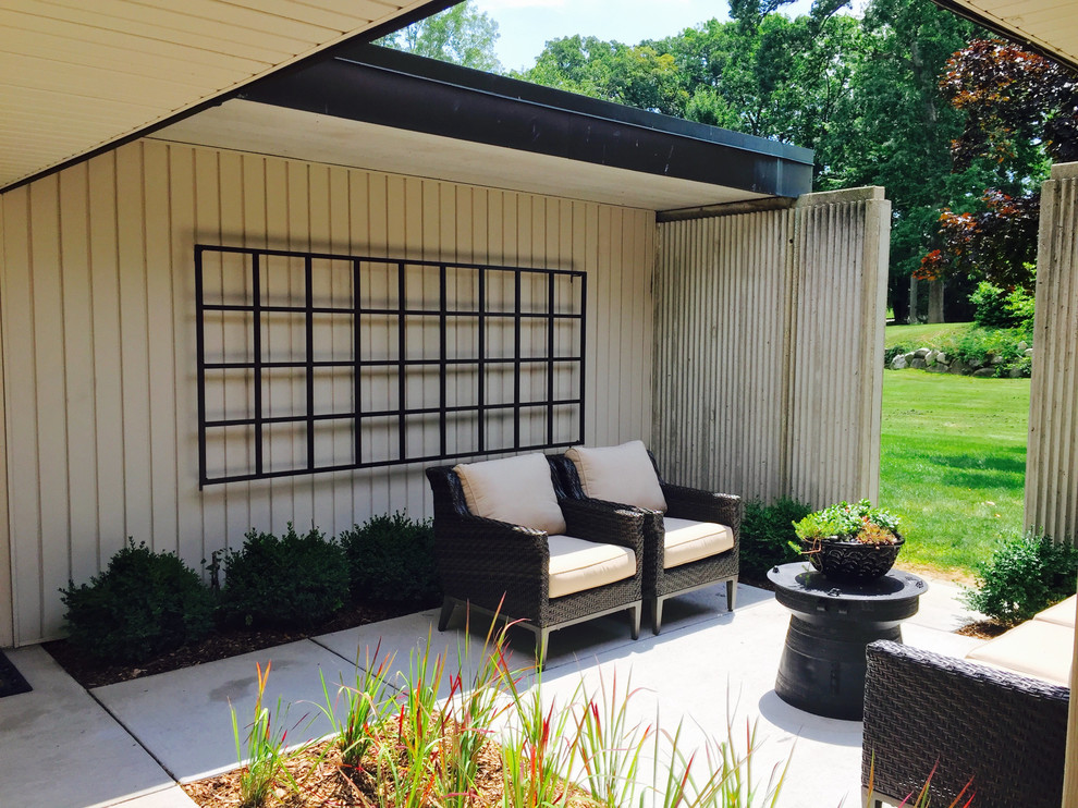 Ejemplo de patio minimalista grande en patio y anexo de casas con jardín vertical y losas de hormigón