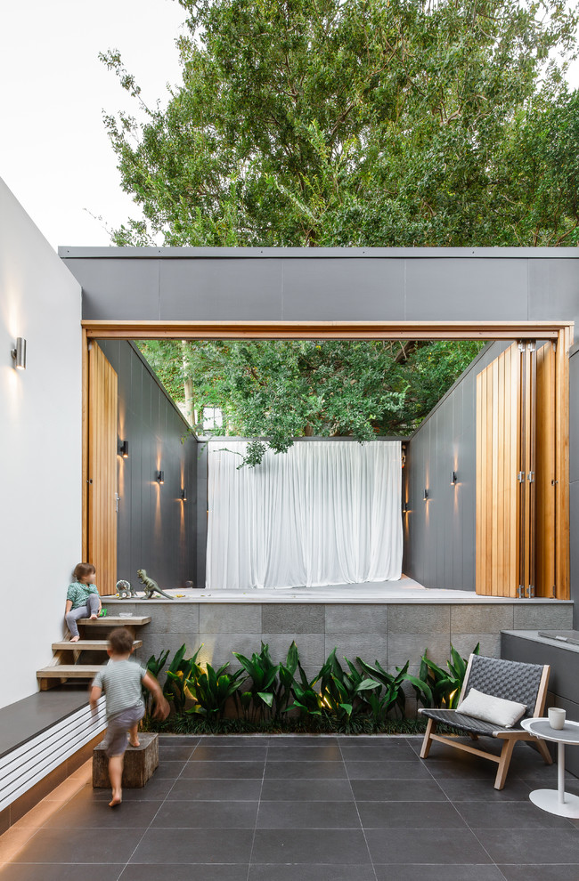 Ispirazione per un patio o portico design dietro casa e di medie dimensioni con nessuna copertura, un giardino in vaso e piastrelle