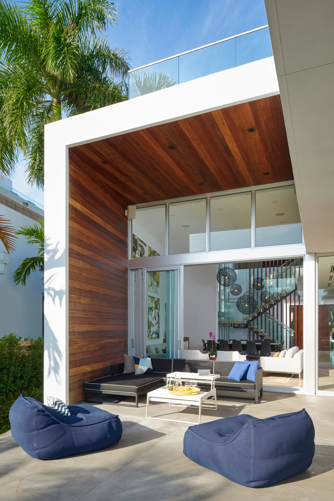 Inspiration for a contemporary back patio in Miami with concrete slabs and a roof extension.