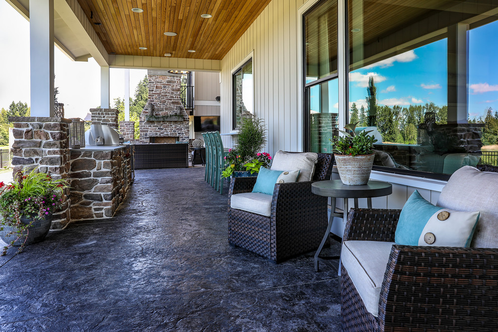 Example of a large cottage backyard concrete patio design in Portland with a fireplace and a roof extension