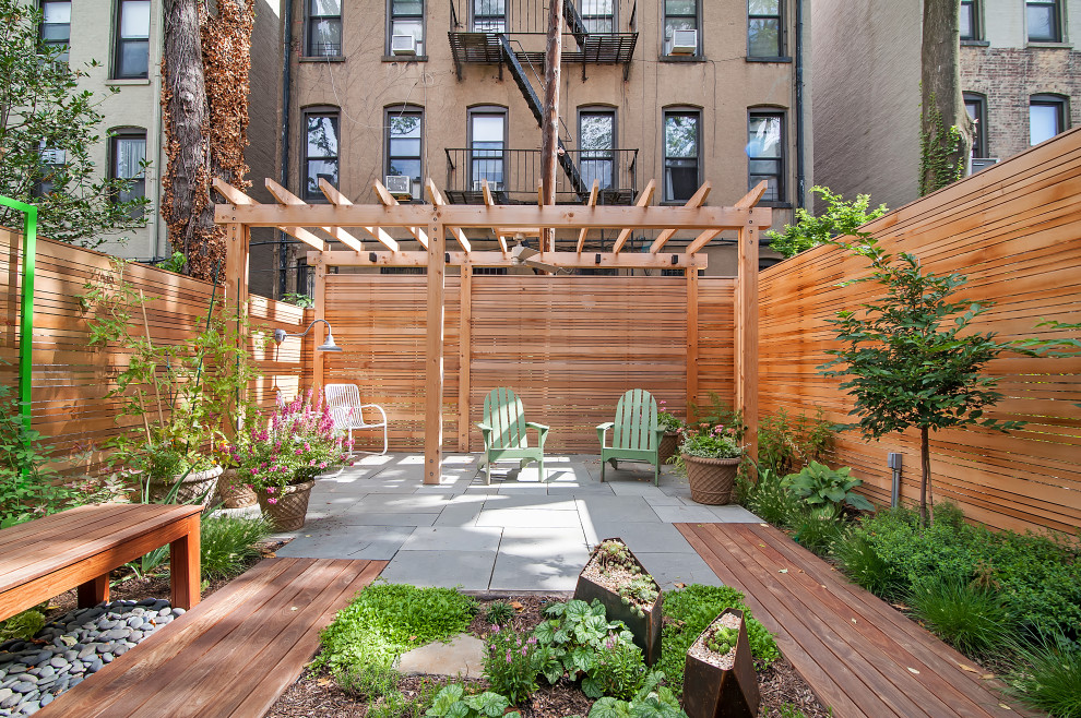 Small trendy backyard stone patio photo in New York with a pergola
