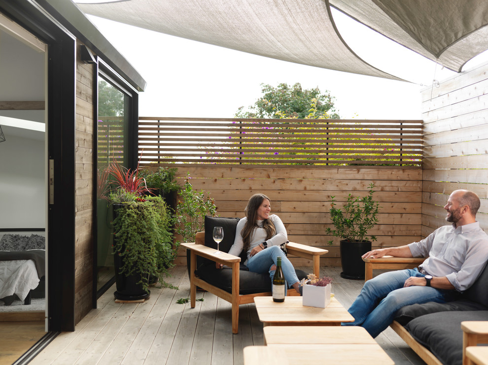 Ejemplo de patio de estilo americano de tamaño medio en patio trasero con entablado y toldo