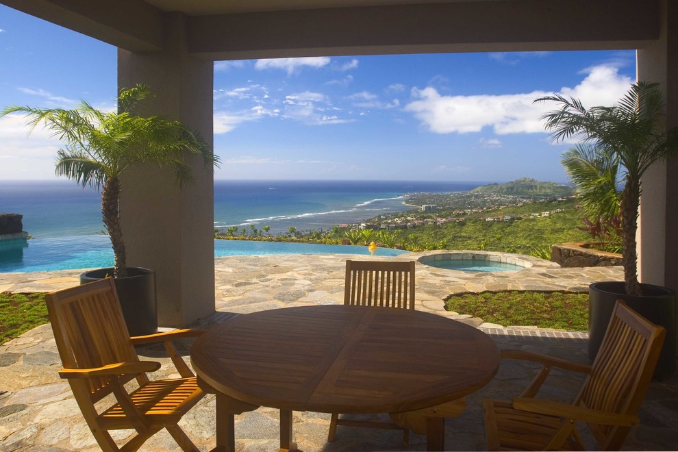 Design ideas for a large world-inspired back patio in Hawaii with natural stone paving and a roof extension.