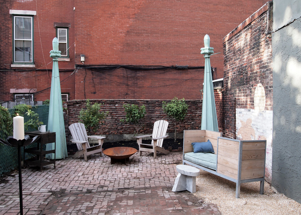This is an example of an eclectic back patio in Philadelphia with brick paving and no cover.