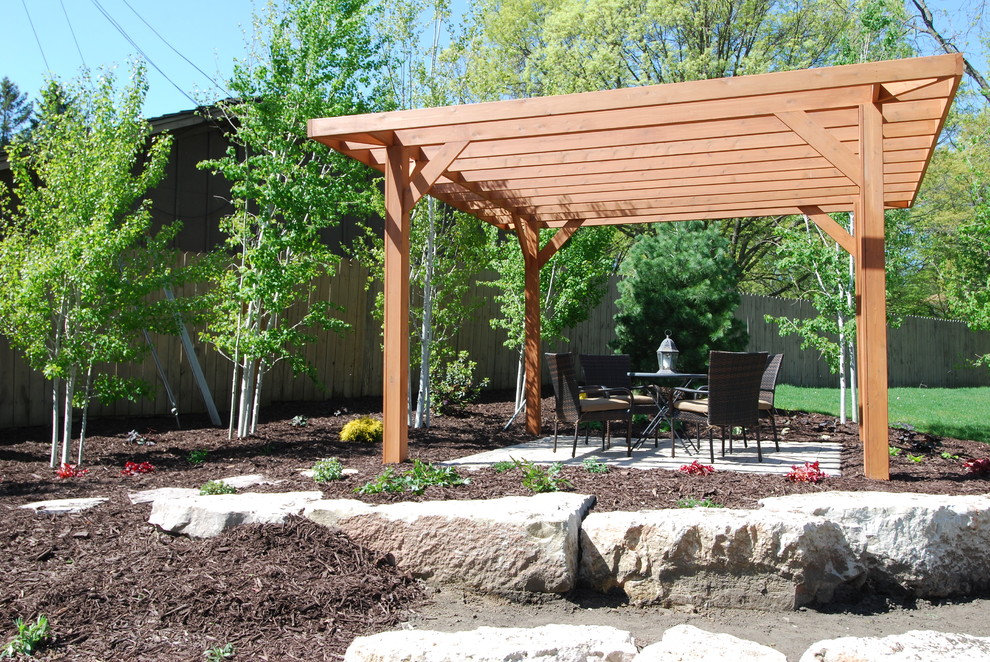 This is an example of a large midcentury back patio in Minneapolis with natural stone paving and a pergola.