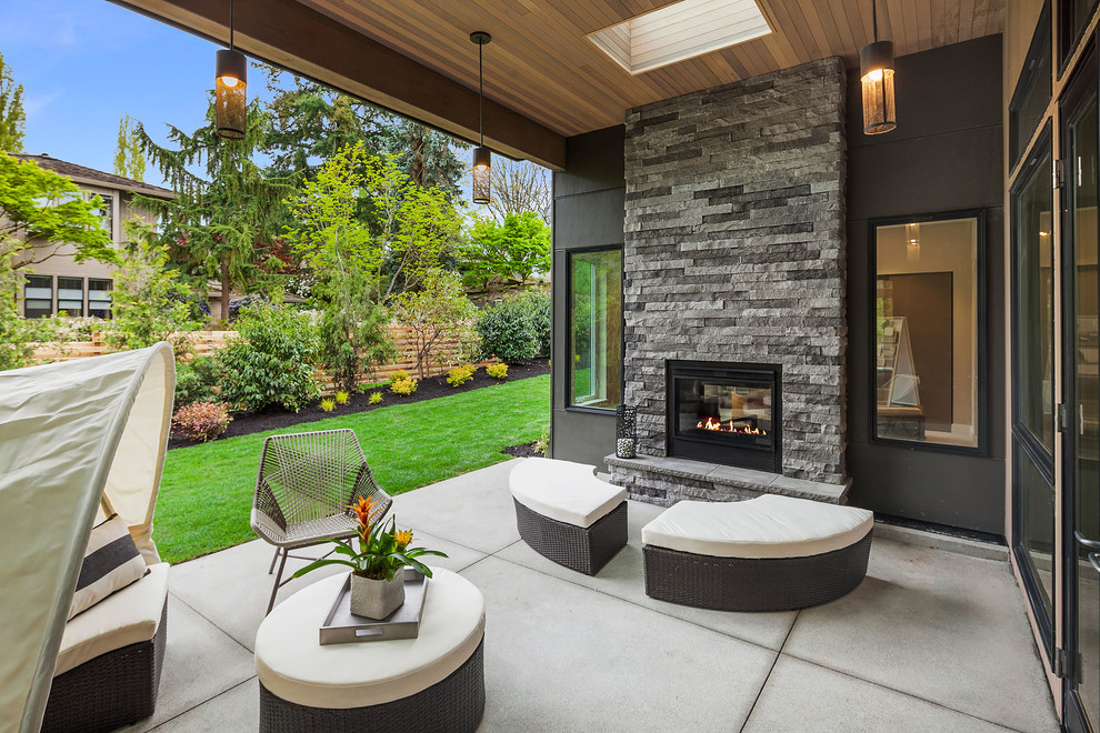 На фото: двор в современном стиле с местом для костра, покрытием из бетонных плит и навесом