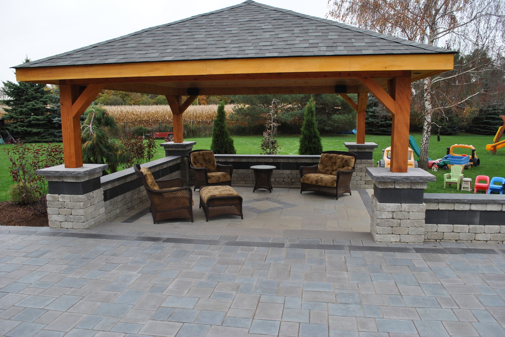 Immagine di un grande patio o portico stile americano dietro casa con un focolare, pavimentazioni in pietra naturale e un gazebo o capanno