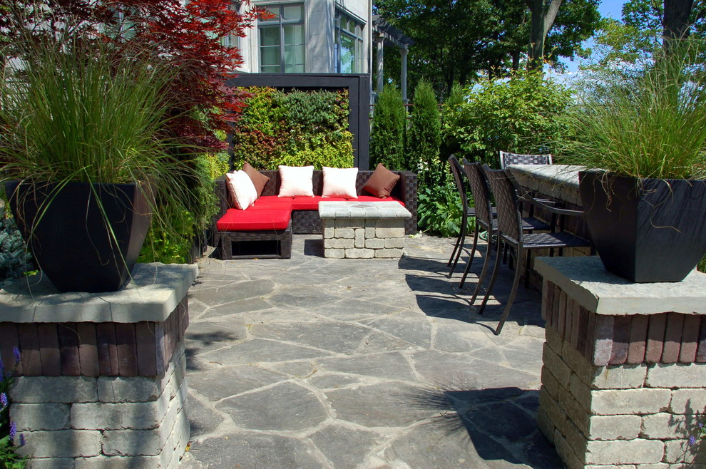Ejemplo de patio actual grande con jardín vertical y adoquines de piedra natural