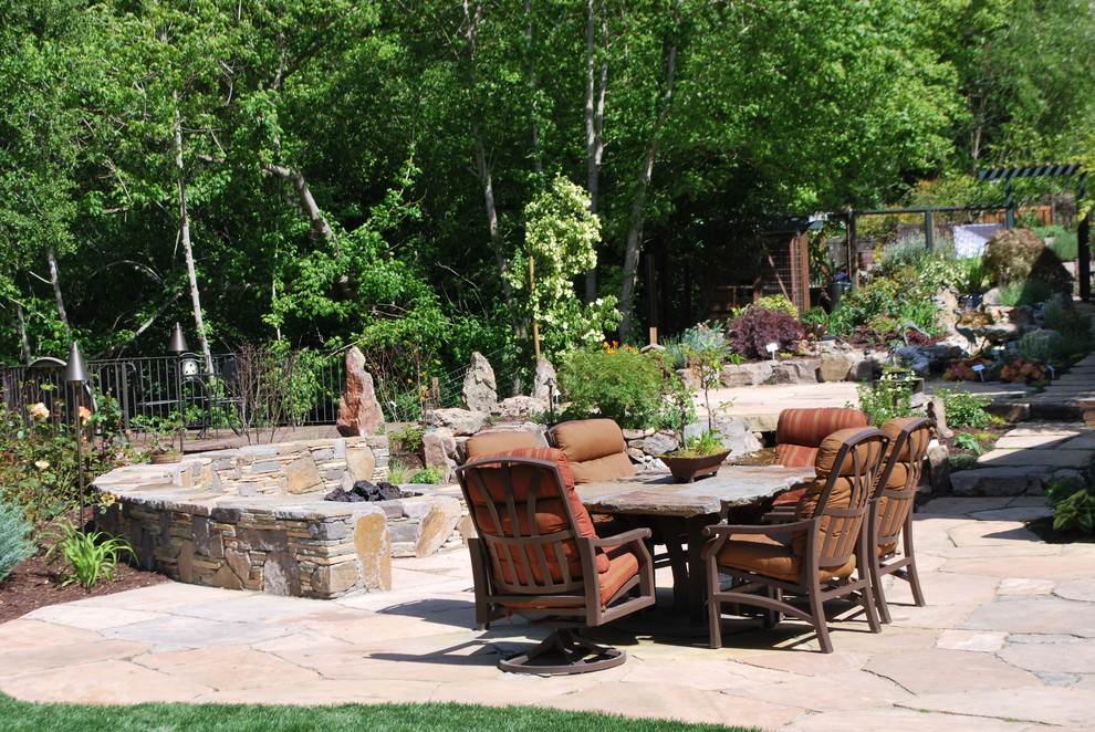 Foto di un patio o portico chic di medie dimensioni e dietro casa con un focolare e pavimentazioni in pietra naturale