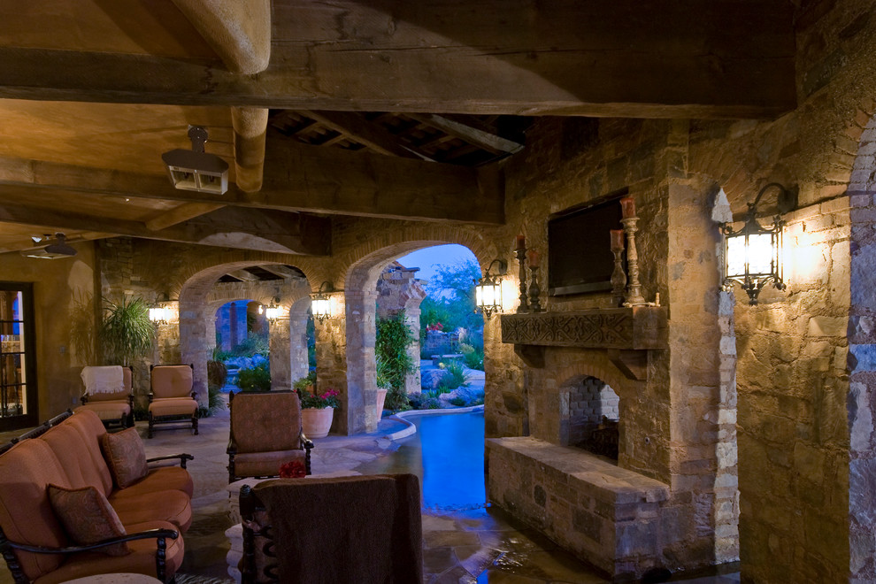 Inspiration for a large mediterranean backyard stone patio remodel in Phoenix with a fire pit and a roof extension