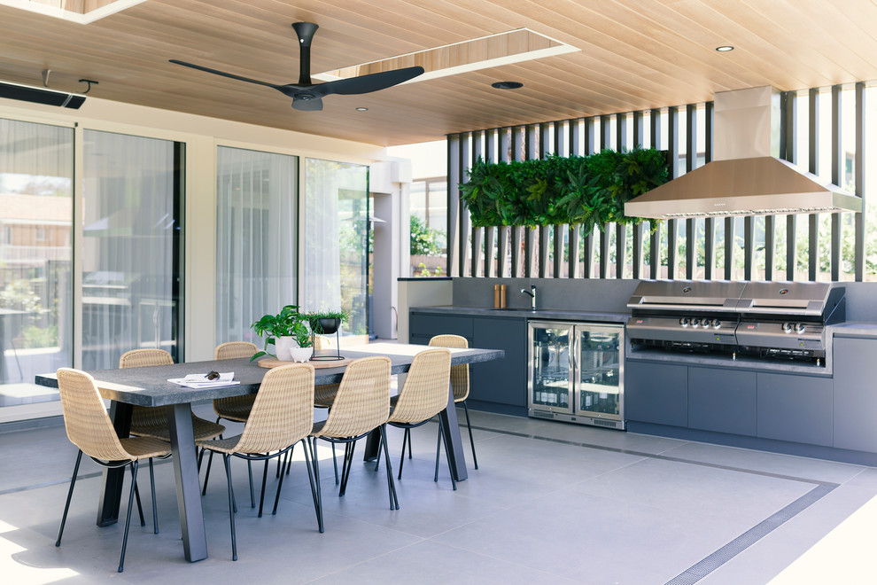 Aménagement d'une terrasse arrière contemporaine avec une cuisine d'été et une extension de toiture.