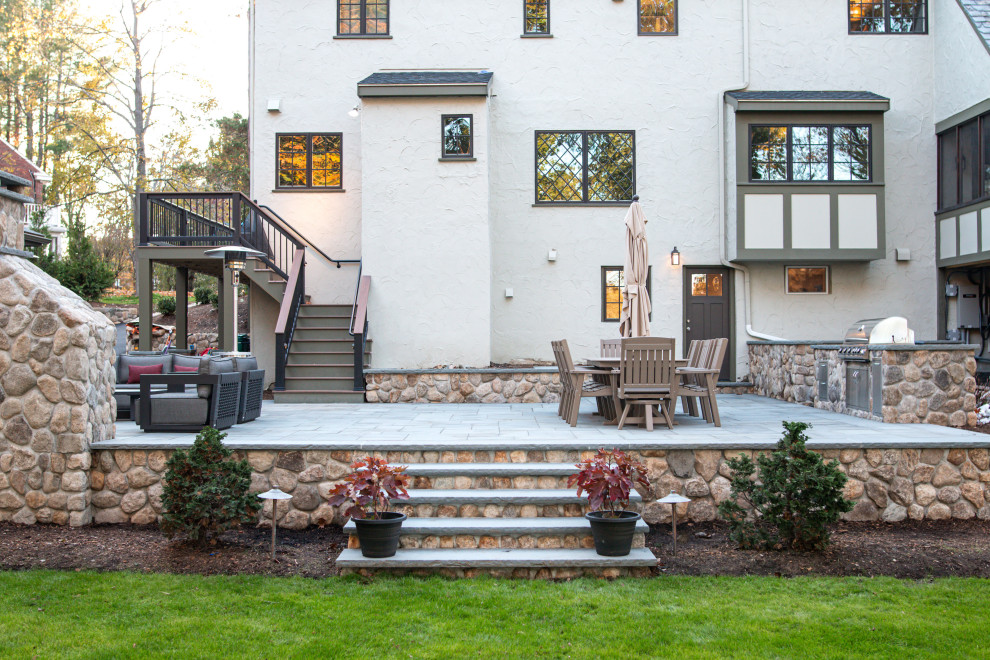 Modelo de patio de estilo de casa de campo grande en patio trasero con cocina exterior y adoquines de piedra natural
