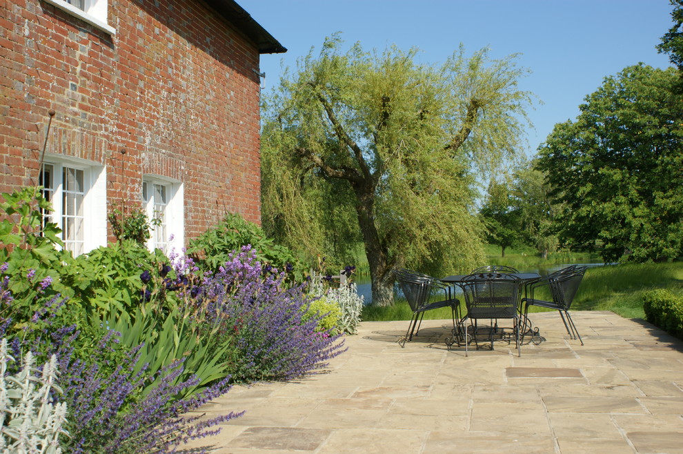 Farmhouse patio in Sussex with natural stone paving and no cover.