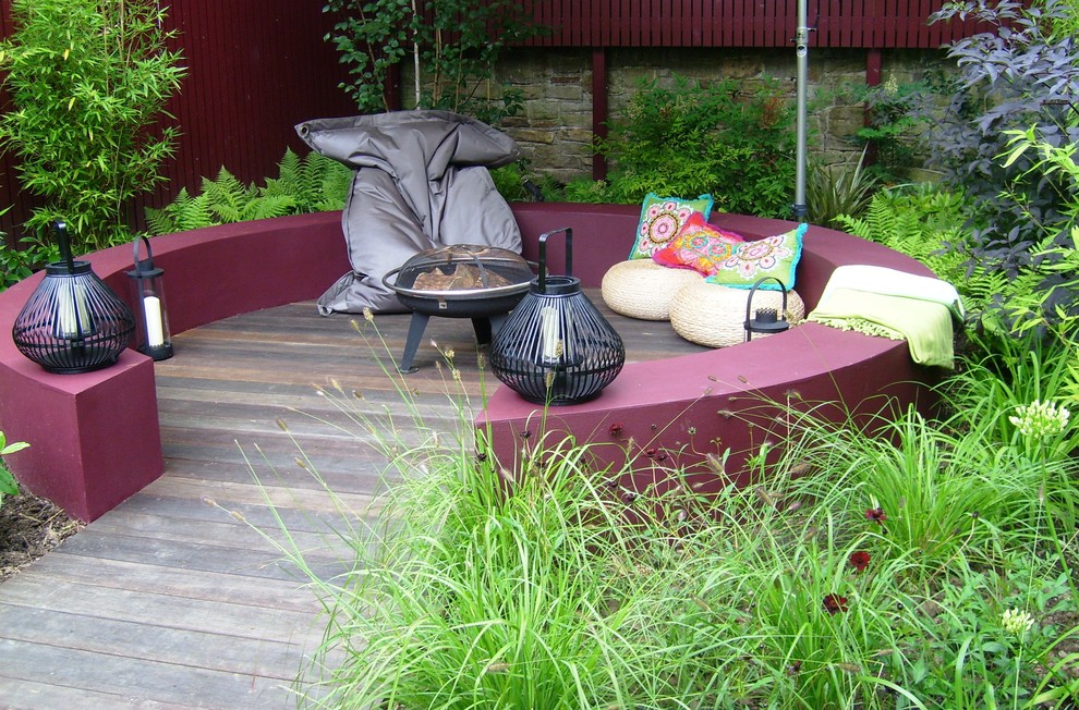 Cette image montre une terrasse arrière minimaliste de taille moyenne avec un foyer extérieur et des pavés en pierre naturelle.