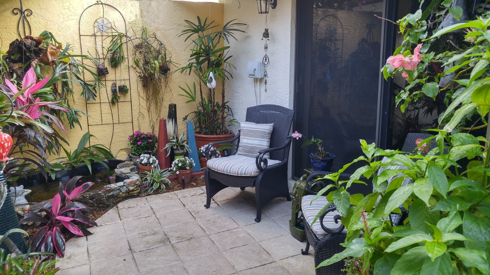 Small eclectic courtyard patio in Miami with a living wall, an awning and stamped concrete.