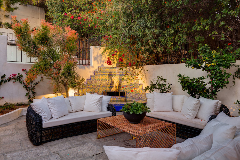 Diseño de patio mediterráneo de tamaño medio sin cubierta en patio trasero con fuente y adoquines de hormigón