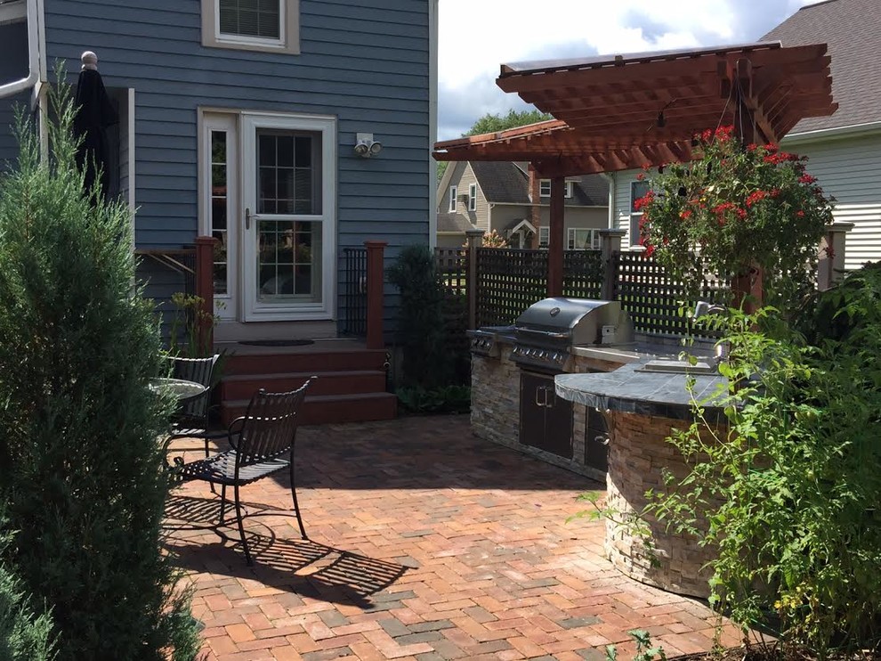 Foto de patio clásico de tamaño medio en patio trasero con cocina exterior, adoquines de ladrillo y pérgola