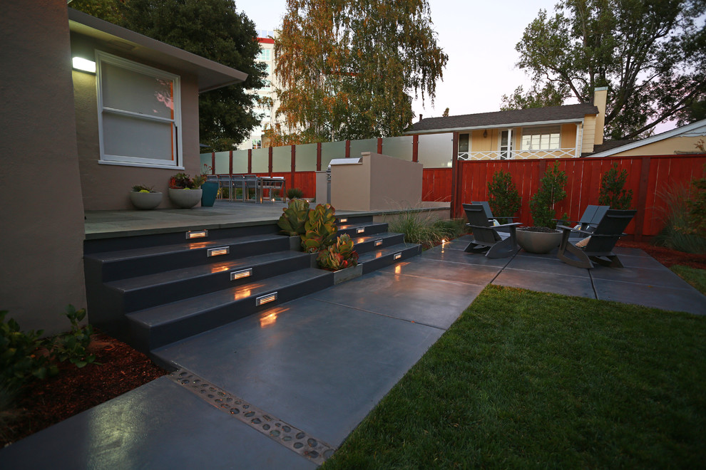 Cette photo montre une grande terrasse arrière moderne avec une cuisine d'été et une dalle de béton.