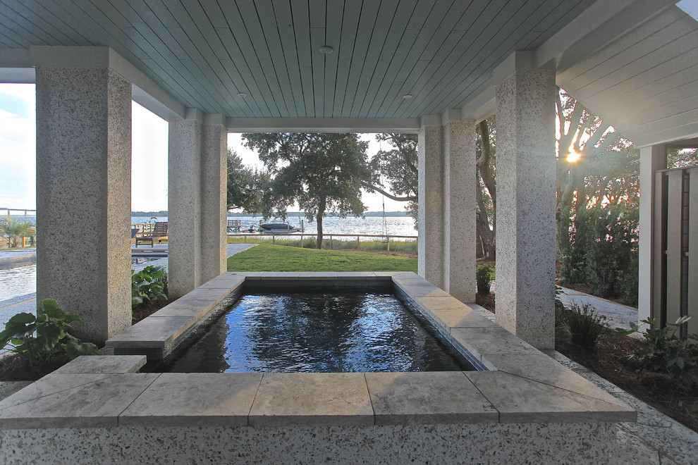 Photo of a large contemporary back patio in Charleston with a water feature, natural stone paving and a roof extension.