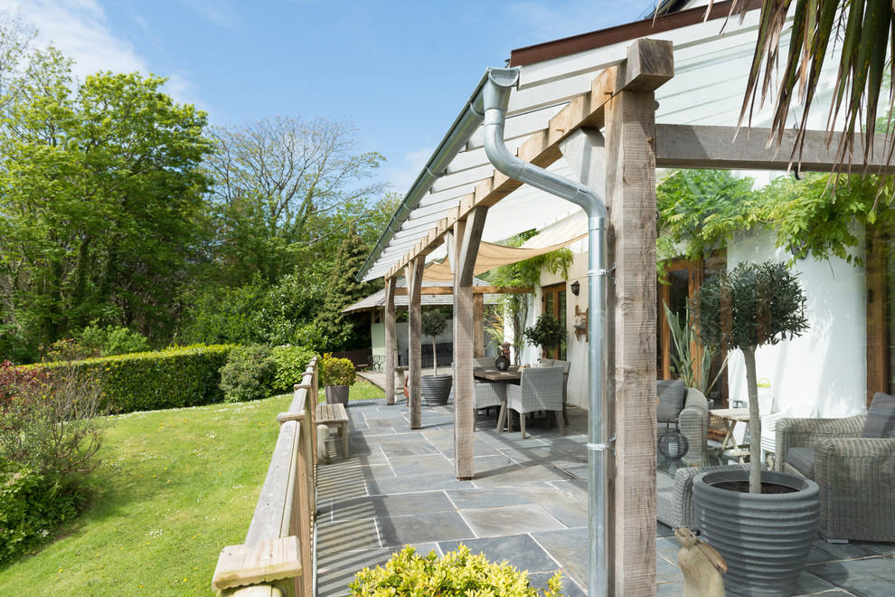 Photo of a large country back patio in Devon with tiled flooring and an awning.