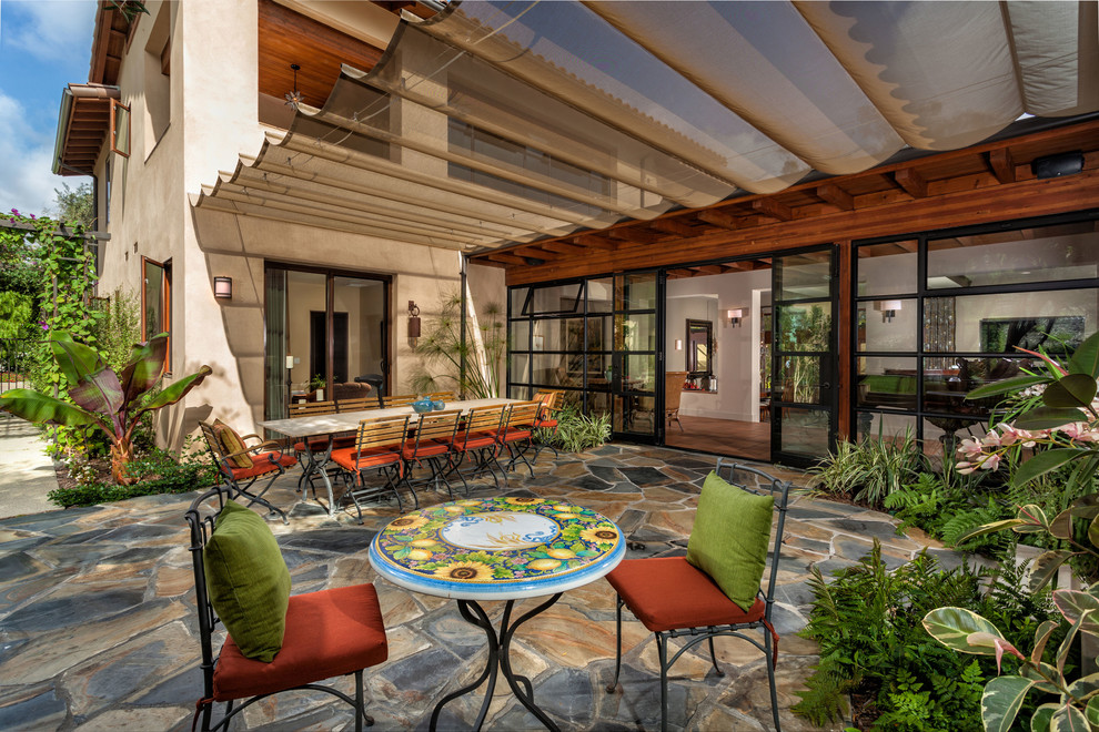 Mediterranean patio in Orange County with natural stone paving and an awning.