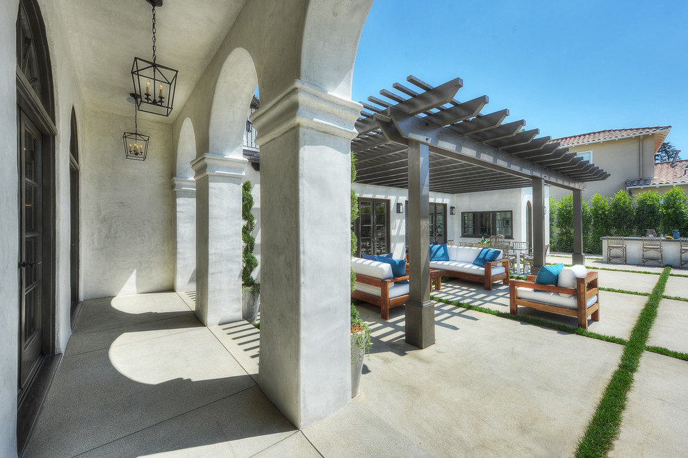 Idee per un grande patio o portico mediterraneo dietro casa con pavimentazioni in cemento e una pergola