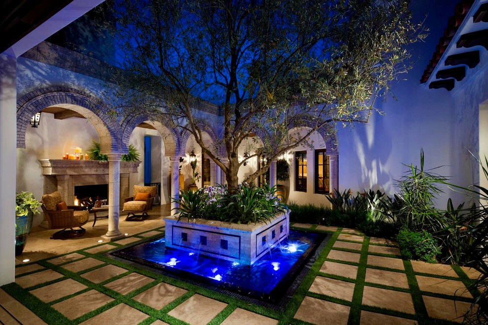 На фото: двор на внутреннем дворе в средиземноморском стиле с фонтаном с
