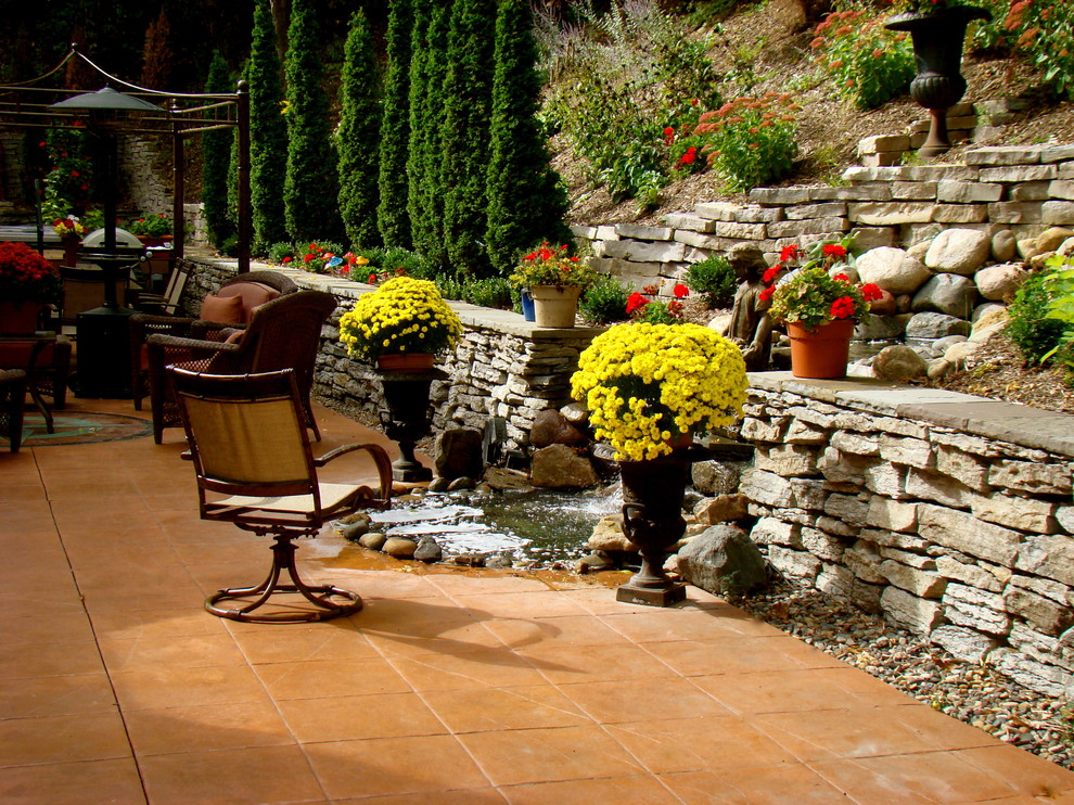 Modelo de patio ecléctico grande en patio trasero con fuente, suelo de hormigón estampado y cenador