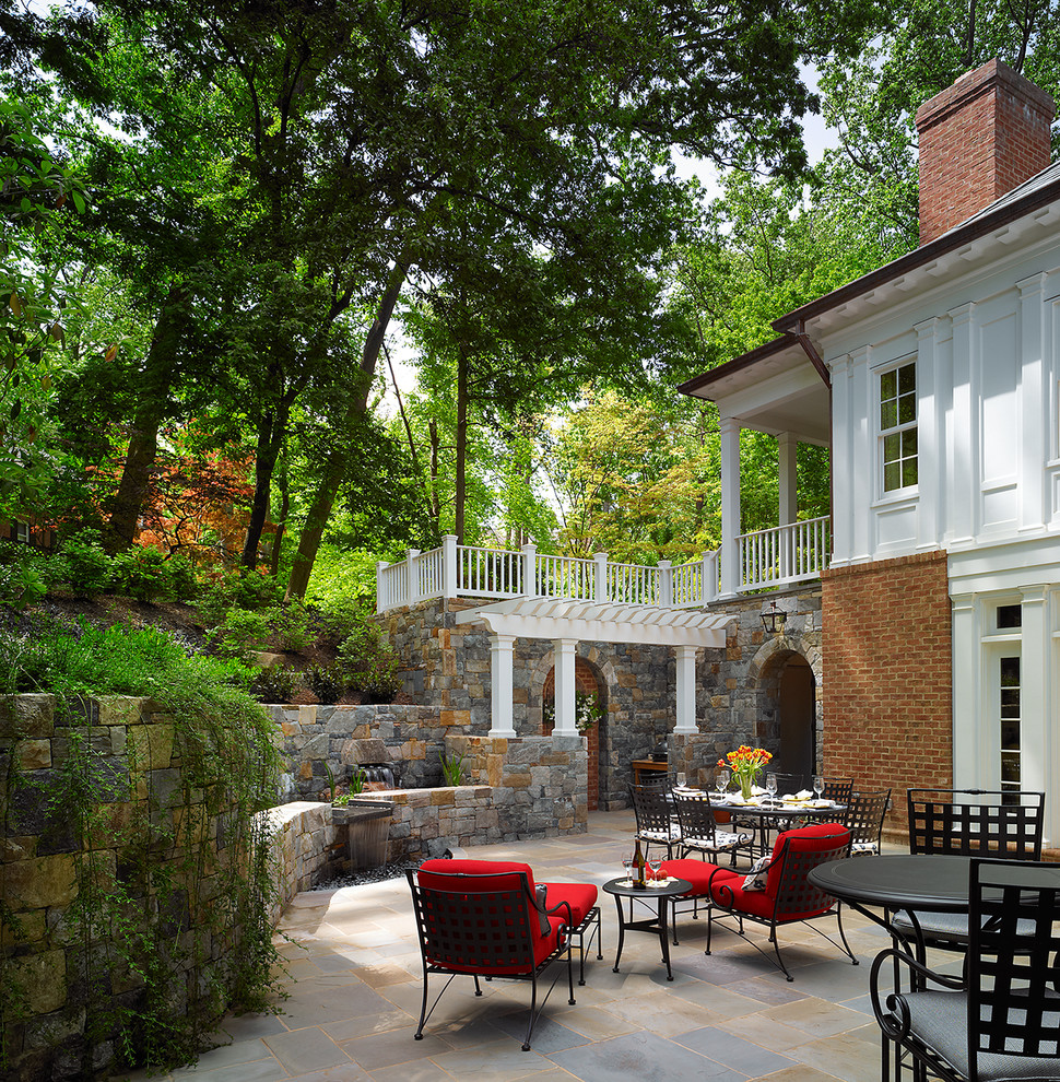 This is an example of a large traditional courtyard patio in DC Metro with no cover, a living wall and natural stone paving.