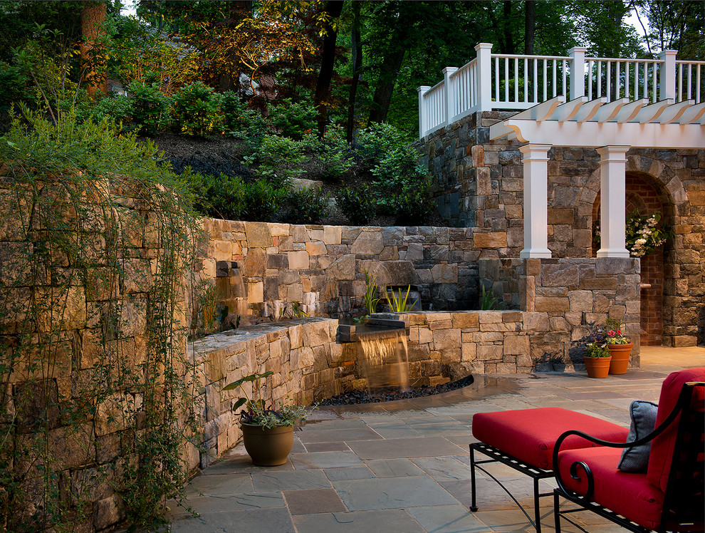 Diseño de patio tradicional de tamaño medio en patio trasero con fuente, adoquines de piedra natural y pérgola