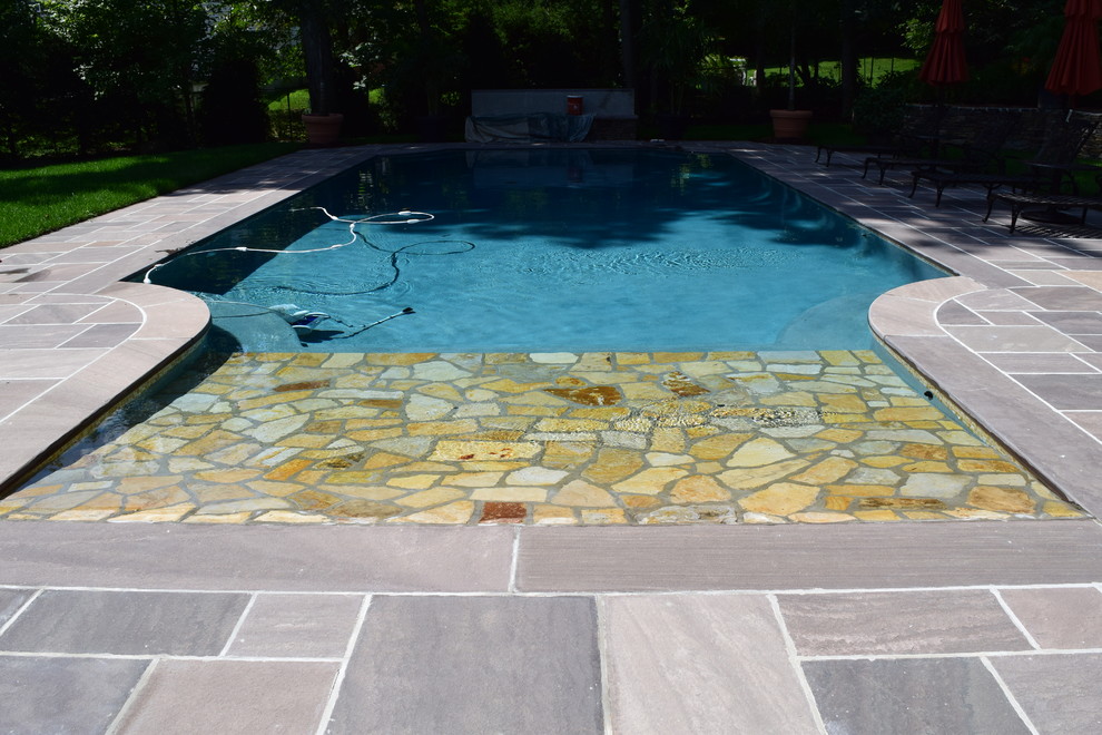 Diseño de piscina con fuente rural de tamaño medio en patio trasero con adoquines de piedra natural