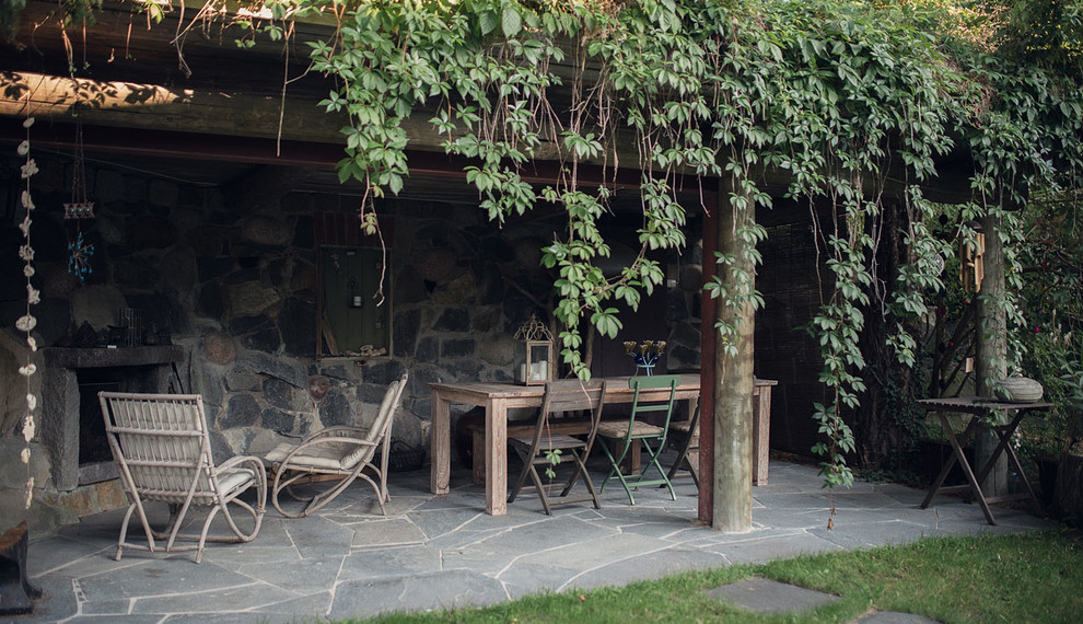 Cette image montre une terrasse arrière chalet avec des pavés en pierre naturelle, un auvent et une cheminée.