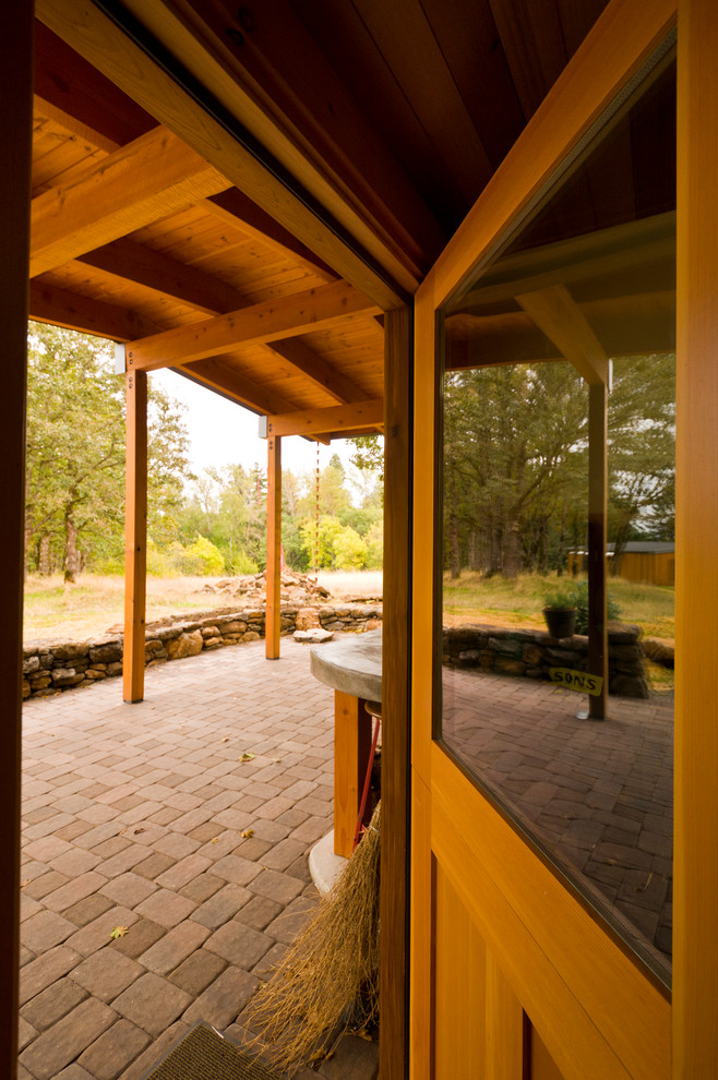 Immagine di un piccolo patio o portico contemporaneo davanti casa con pavimentazioni in mattoni e un tetto a sbalzo