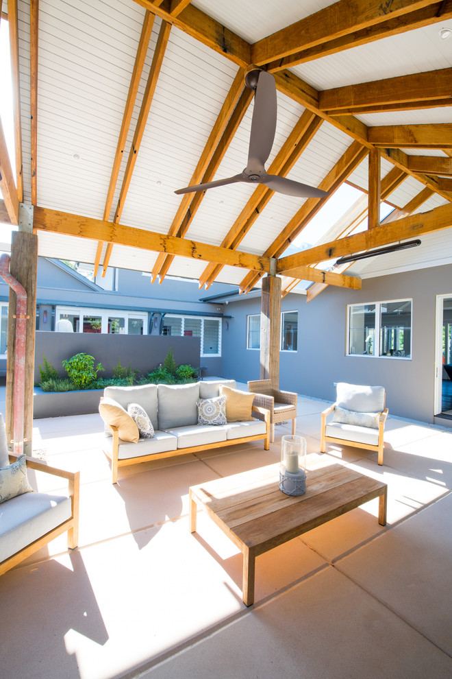 This is an example of a large contemporary courtyard patio in Sunshine Coast with concrete paving and an awning.