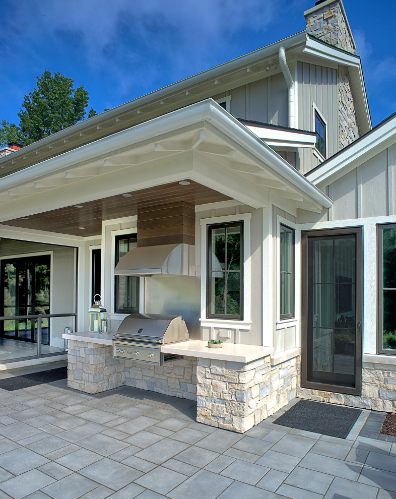 Patio kitchen - country backyard stone patio kitchen idea in Grand Rapids with a roof extension