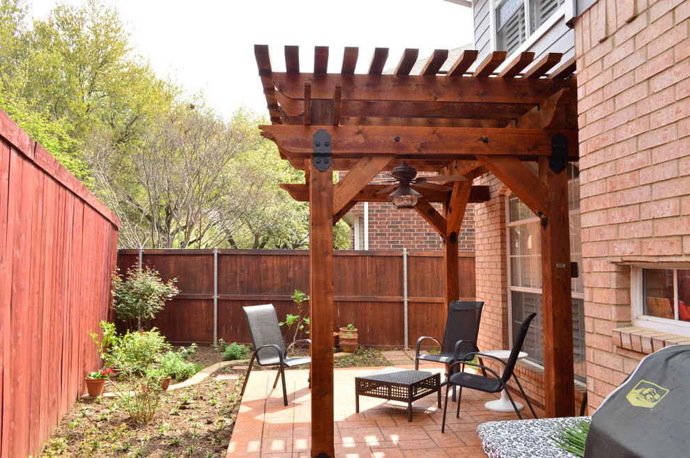 Esempio di un patio o portico rustico di medie dimensioni e nel cortile laterale con cemento stampato e una pergola