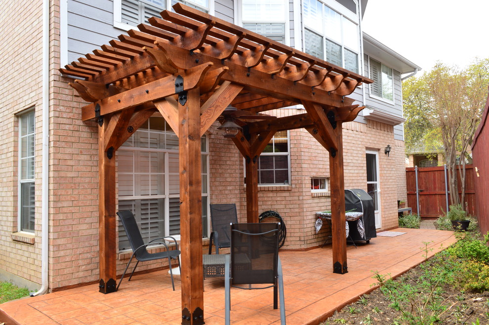Esempio di un patio o portico rustico di medie dimensioni e nel cortile laterale con cemento stampato e una pergola