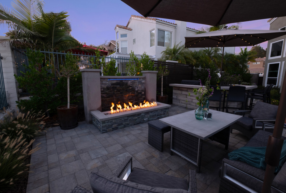 This is an example of a medium sized traditional back patio in Orange County with a fireplace, concrete paving and a roof extension.