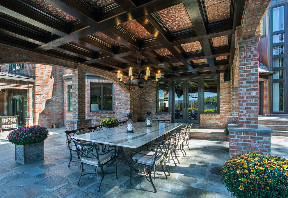 На фото: двор на заднем дворе в классическом стиле с навесом и покрытием из каменной брусчатки