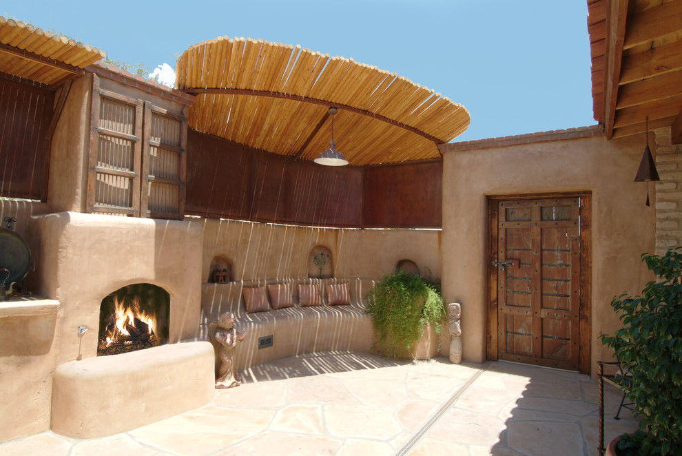 Cette photo montre une terrasse latérale sud-ouest américain de taille moyenne avec un foyer extérieur, un auvent et des pavés en béton.