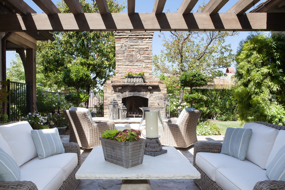 Foto de patio clásico renovado de tamaño medio en patio trasero con brasero, adoquines de piedra natural y pérgola
